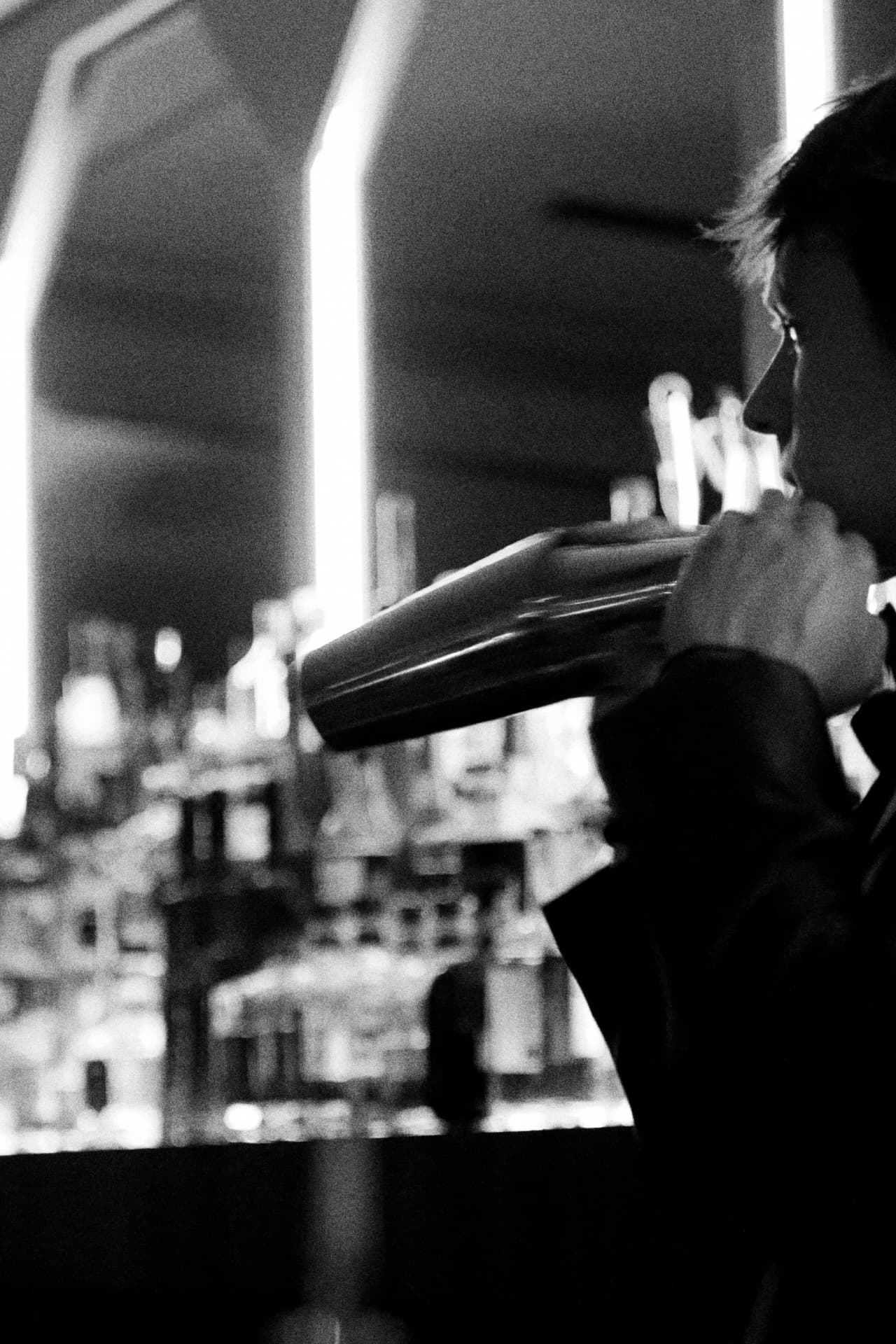 Bartender shaking a cocktail behind a bar, black and white