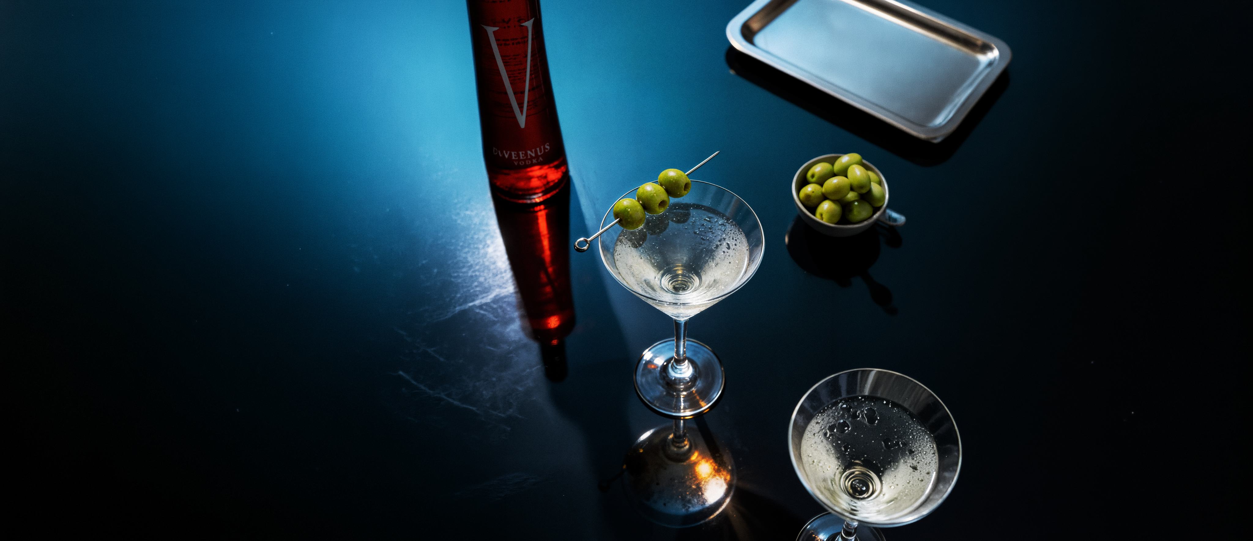 Veenus bottle with martini cocktails on a dark surface